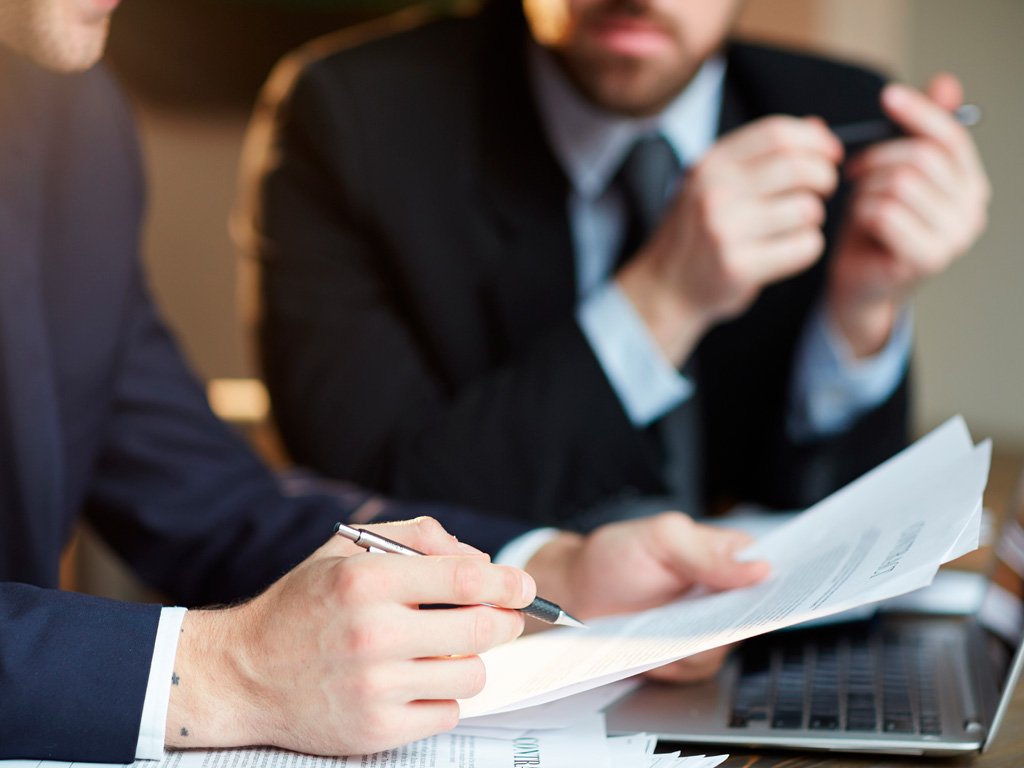 Duas pessoas lendo um documento em ambiente iluminado, representando o ato de autorizar legalmente alguém a agir em nome de outra.