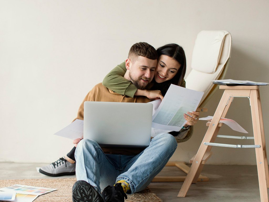 Casal sorridente sentado lado a lado, analisando juntos um documento, simbolizando a formalização da união estável.